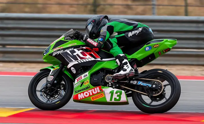 Focused MotoGP rider huddled over his motorcycle
