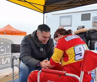 Fisioterapeuta masajea el brazo de un motociclista antes de la carrera