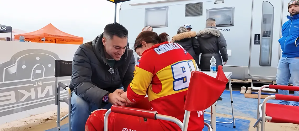 Un hombre le da un masaje en el antebrazo a un piloto de motociclismo