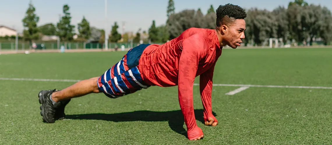 Lean guy doing push ups in a football field