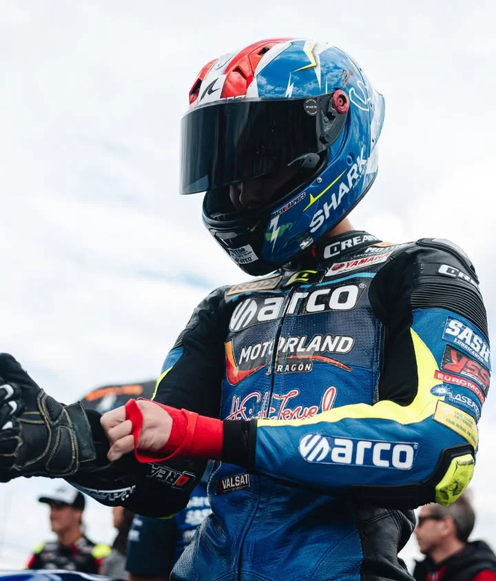 Piloto de MotoGP con traje azul poniéndose los guantes